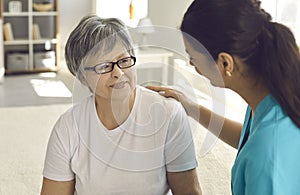Portrait of female nurse caregiver putting hand on senior woman patient shoulder