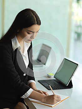 Female office worker in black suit planing her schedule on office table
