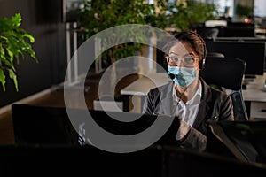 Portrait of a female operator Call Center wearing a medical mask for the desktop