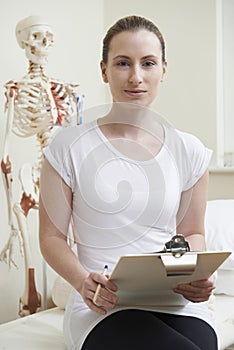 Portrait Of Female Osteopath In Consulting Room