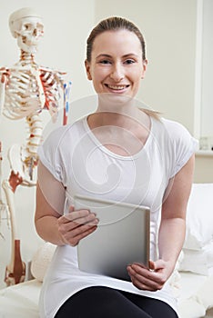 Portrait Of Female Osteopath In Consulting Room With Digital Tab