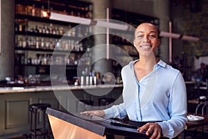 Portrait Of Female Owner Of Restaurant Bar Standing At Counter Using Digital Tablet