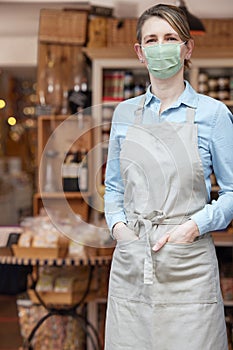 Portrait Of Female Owner Standing Outside Delicatessen Wearing Face Mask During Health Pandemic