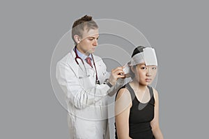 Portrait of female patient with doctor wrapping bandage to her head