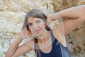 Portrait of female person in one-piece swimsuit against rock