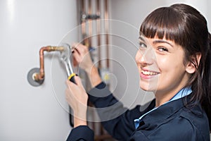 Portrait Of Female Plumber Working On Central Heating Boiler