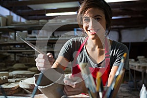 Portrait of female potter carving mug