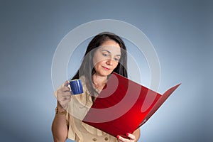 Portrait of female professional reading a document and drinking coffee