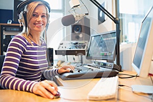 Portrait of female radio host using computer in studio