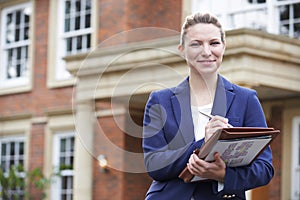 Portrait Of Female Realtor Standing Outside Residential Property