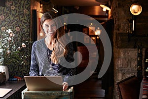 Portrait Of Female Receptionist Working On Laptop At Hotel Check In