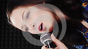 Portrait of female singing song into professional microphone. Vertical video