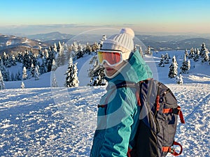 PORTRAIT: Female snowboarder wearing orange goggles smiles before descent.