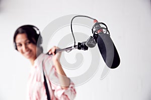 Portrait Of Female Sound Recordist Holding Microphone On Video Film Production In White Studio photo