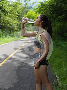 Portrait of female in sport ware drinking water after morning run