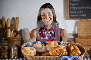 Portrait of female staff holding basket of sweet foods