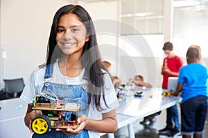 Portrait Of Female Student Building Robot Vehicle In After School Computer Coding Class