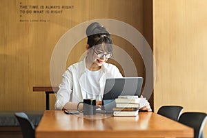 Portrait of female student researching for her thesis with digital tablet and books in library