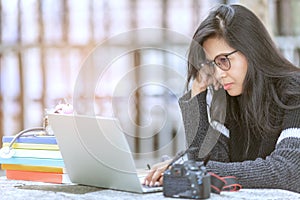 Portrait of female student sitting at the park and using laptop