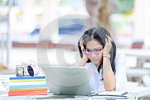 Portrait of female student sitting at the park and using laptop.