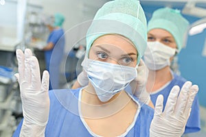 Portrait female surgeon showing surgical gloves in operation room