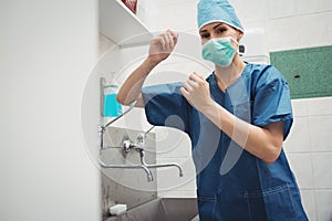 Portrait of female surgeon washing hands prior to operation using correct technique for cleanliness