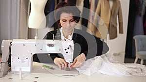 Portrait of female tailor working on sewing machine. Caucasian woman using a sewing machine at studio or in workshop