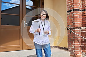 Portrait of female teacher looking at camera outdoor on steps of school building