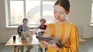 Portrait of female team leader businesswoman standing in office with colleagues meeting in background. Smiling confident