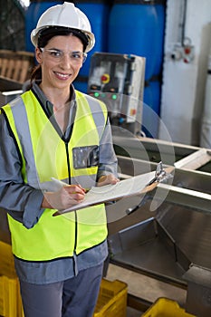 Portrait of female technician writing in clipboard