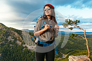 Portrait of a female traveler in the mountains. Adventure, travel and hiking concept. A happy woman in a red cap enjoying