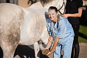 Portrait of female vet examining horse hoof