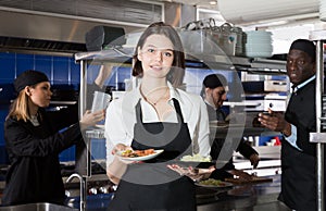 Portrait of female waiter who is standing with order on kitchen