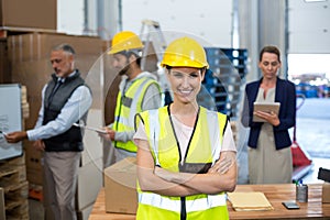 Portrait of female warehouse worker standing with arms crossed