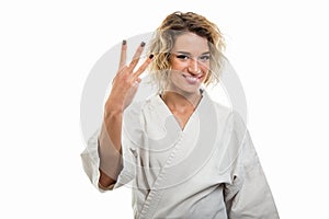 Portrait of female wearing martial arts uniform showing number three