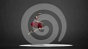 Portrait of female on white background in studio under spotlight. Beautiful ballerina in red tutu and black body jumping