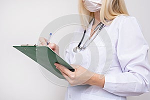 Portrait of a female woman doctor with prescription board in hands and face medical surgical mask on the face