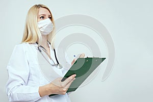 Portrait of a female woman doctor with prescription board in hands and face medical surgical mask on the face