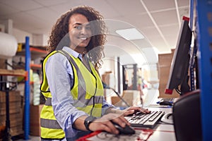 Portrait Of Female Worker In Busy Modern Warehouse Working On Computer Terminal