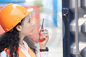 Portrait of female worker In Cargo Containers In Shipping Container Yard. woman holding walkie-talkie and digital tablet