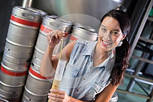 Portrait of female worker examining beer in test tube at factory