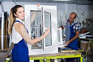 Portrait of female worker with finished plastic window in workshop