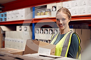 Portrait Of Female Worker Picking Box From Shelf Inside Warehouse 