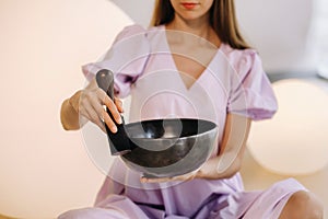 Portrait of a female yoga teacher playing a Tibetan bowl or singing a bell in the gym during a yoga retreat