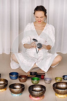 Portrait of a female yoga teacher playing a Tibetan bowl or singing a bell in the gym during a yoga retreat