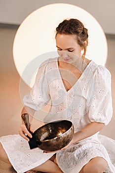 Portrait of a female yoga teacher playing a Tibetan bowl or singing a bell in the gym during a yoga retreat