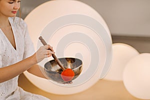 Portrait of a female yoga teacher playing a Tibetan bowl or singing a bell in the gym during a yoga retreat