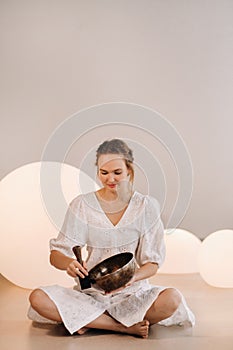 Portrait of a female yoga teacher playing a Tibetan bowl or singing a bell in the gym during a yoga retreat