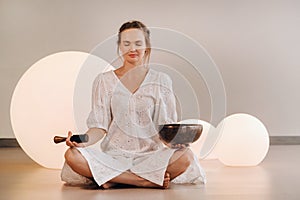 Portrait of a female yoga teacher playing a Tibetan bowl or singing a bell in the gym during a yoga retreat