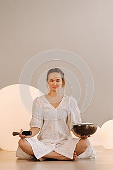 Portrait of a female yoga teacher playing a Tibetan bowl or singing a bell in the gym during a yoga retreat